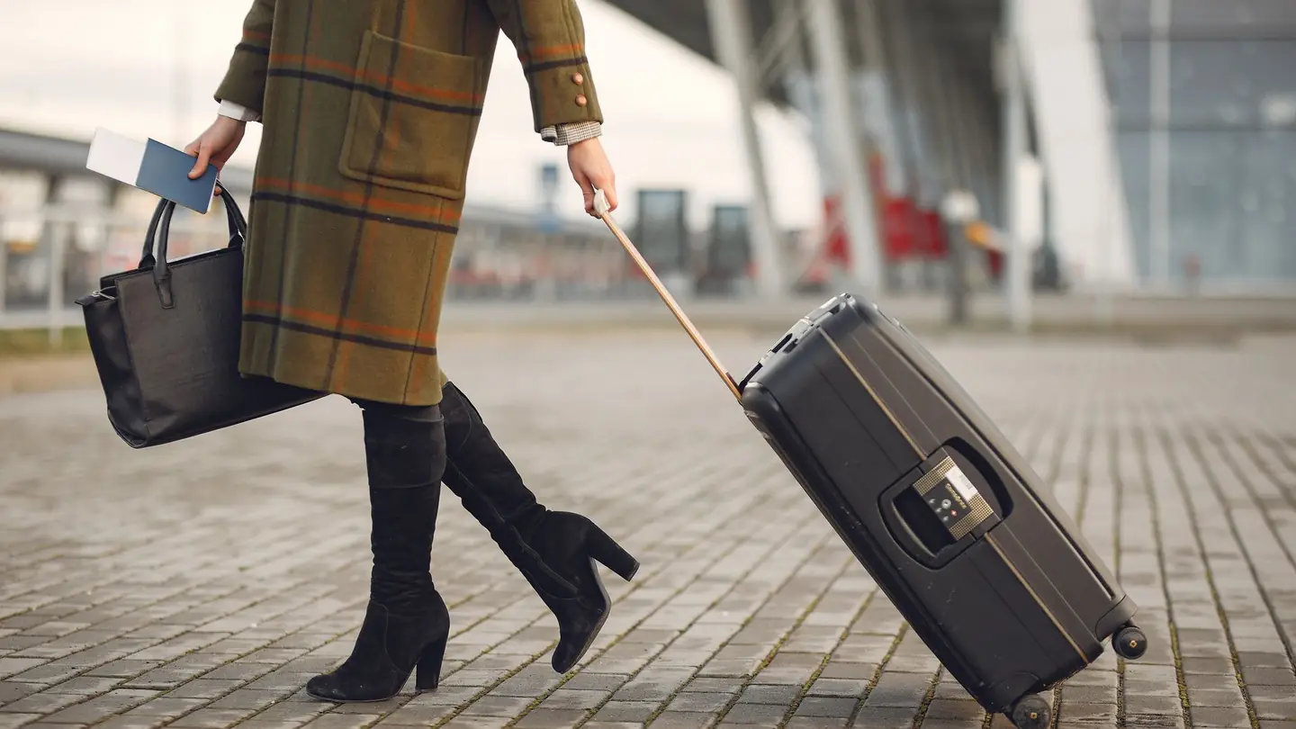 Una viajera con la maleta y el pasaporte en la mano, de camino al hotel.